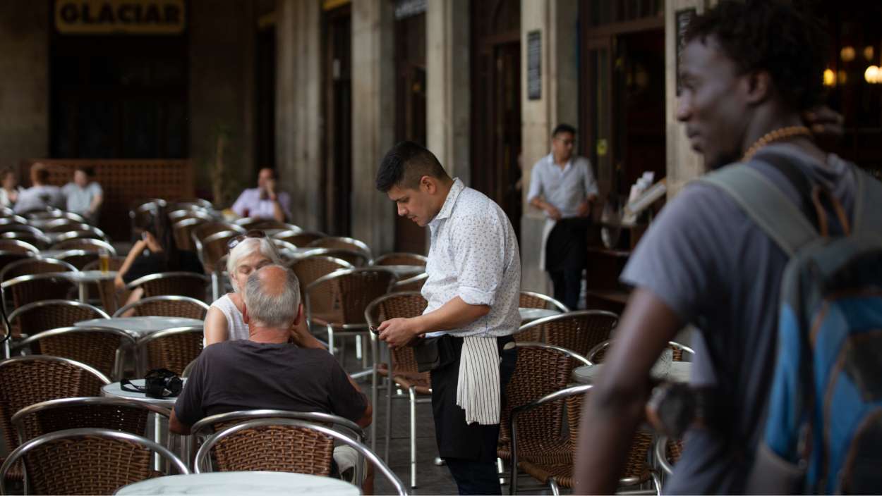 Un cambrer atén una taula a la plaça Reial de Barcelona, el 15 de juny de 2022. David Zorrakino / EP